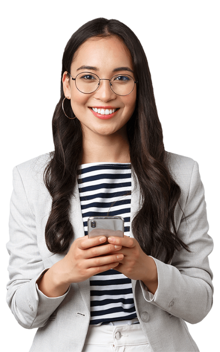 A young woman with long dark hair and glasses, wearing a light blazer over a striped shirt, smiles while holding a smartphone in both hands—ready to share insights from her social media marketing agency.
